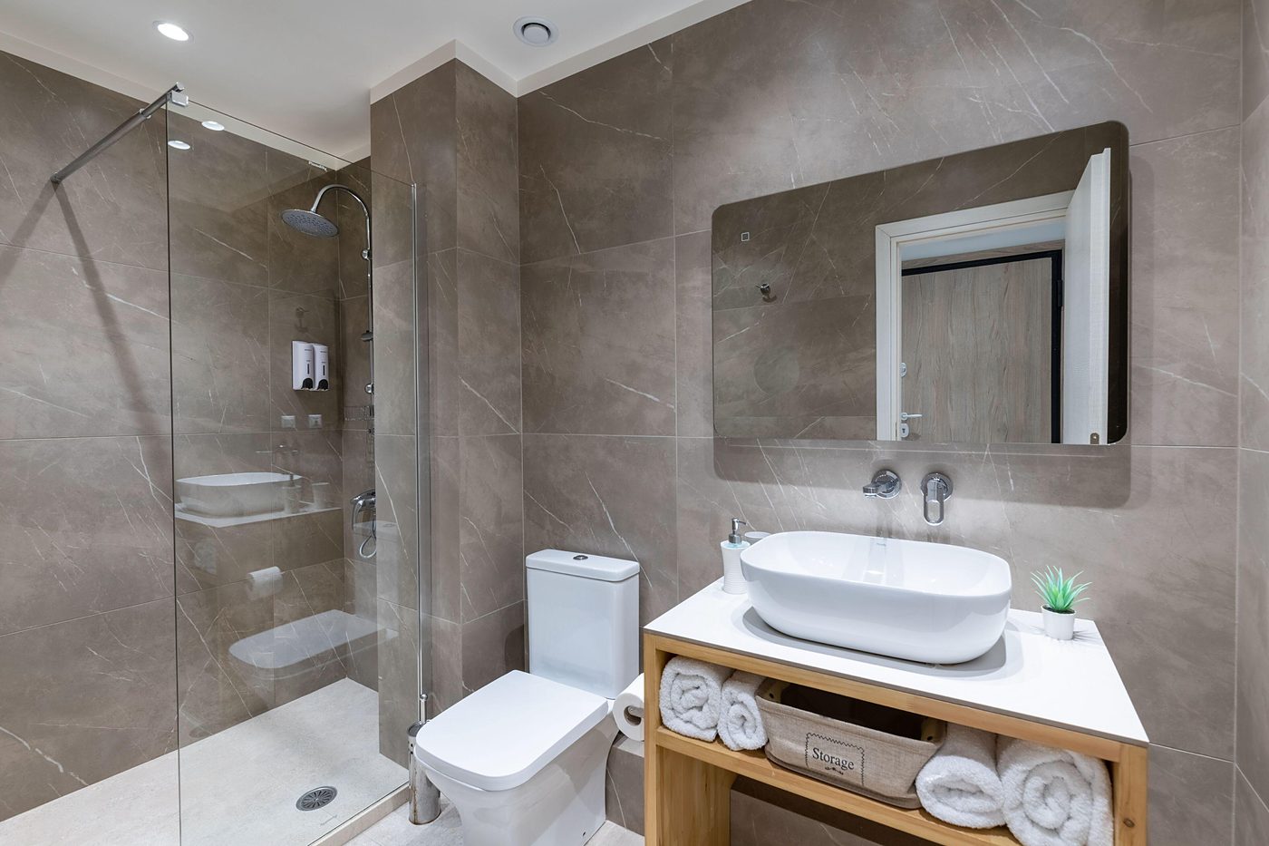 Studio One, The bathroom, glass, stone, towels within reach.