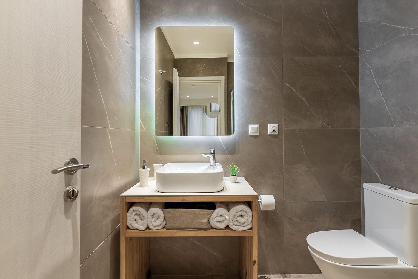 Studio Two, Stone bathroom, warm towels, a backlit mirror.